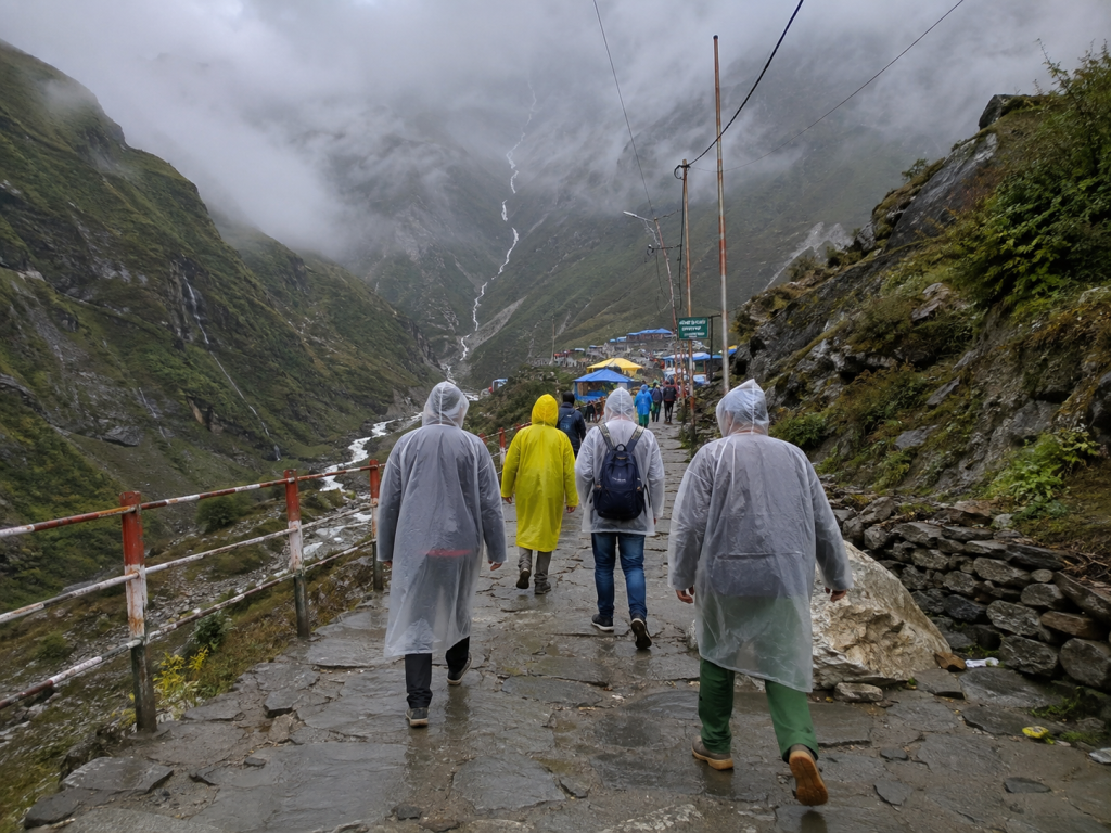 Pilgrims carrying backpacks in changing weather on the Kedarnath route